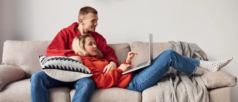 a couple in red sweatshirts looking at laptop